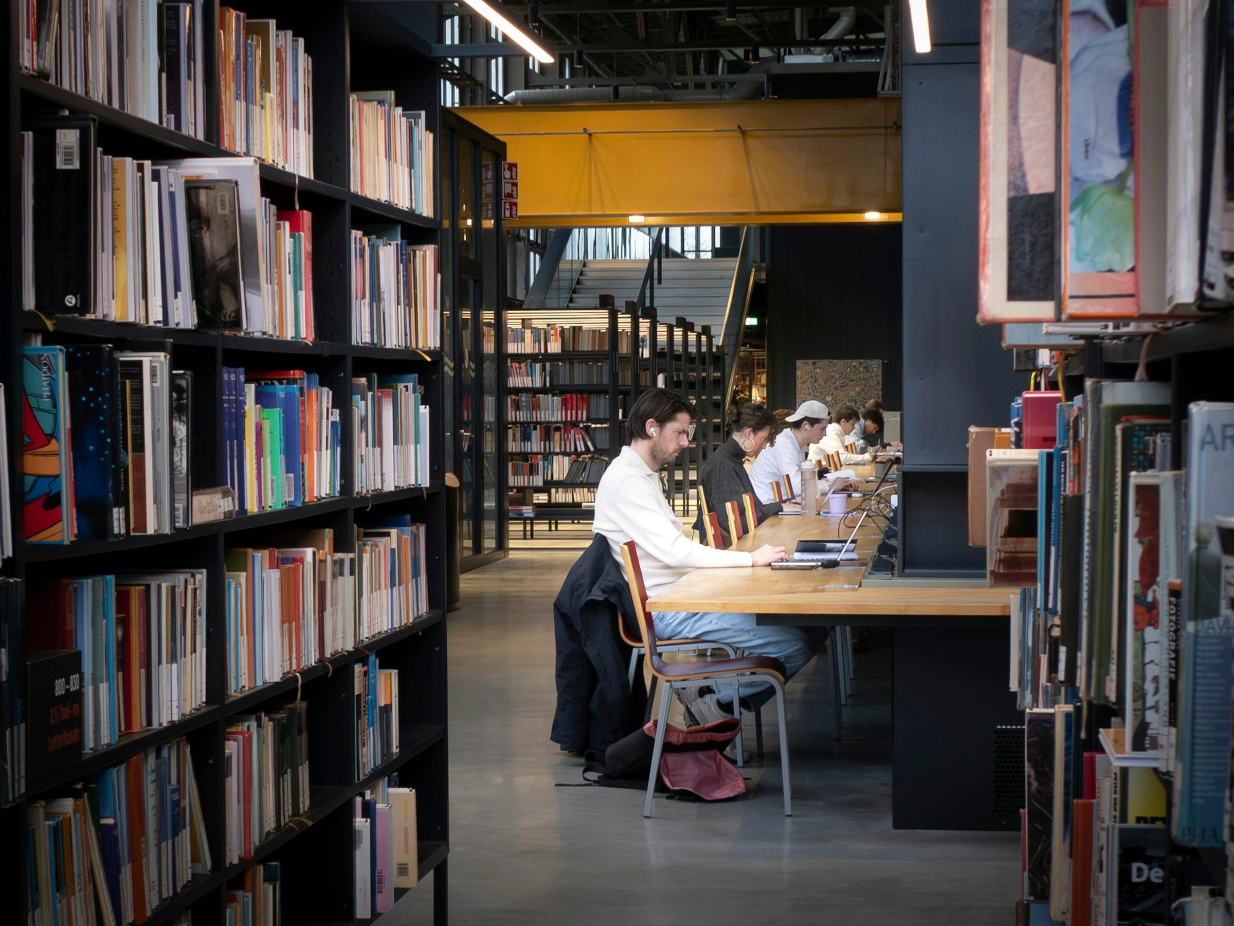 Students at a Middle Eastern university library, study session at a long shared table.